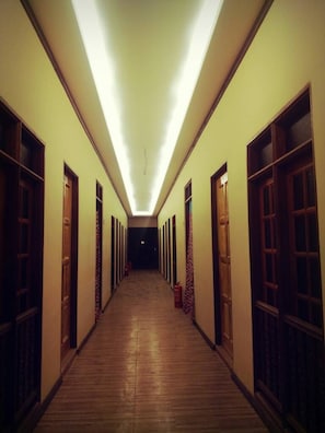 A long, narrow hallway with wooden flooring and doors on both sides, leading to a dark room at the end. - Kembara Resort (Setiu)