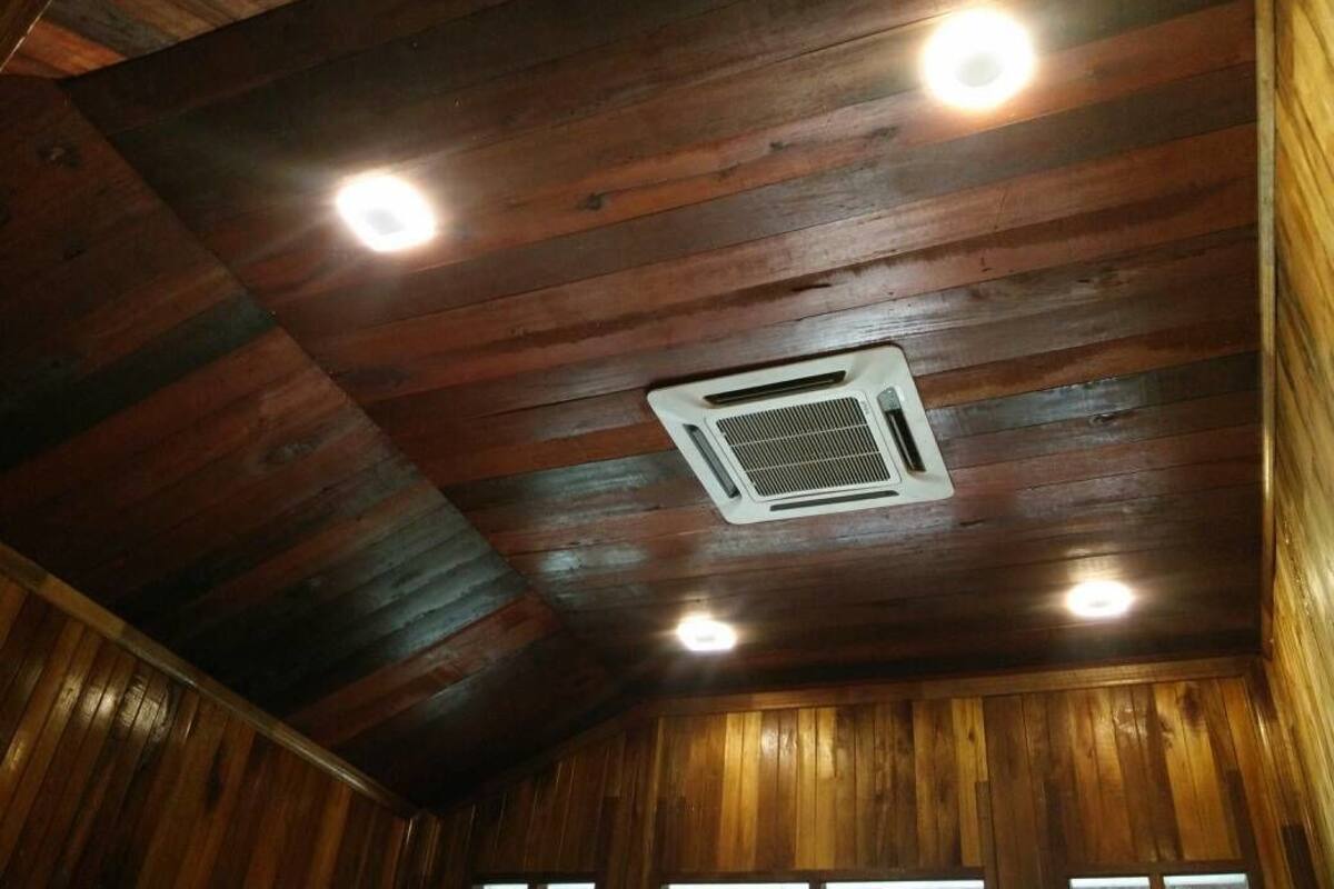 A wooden ceiling with recessed lighting and a ventilation unit.