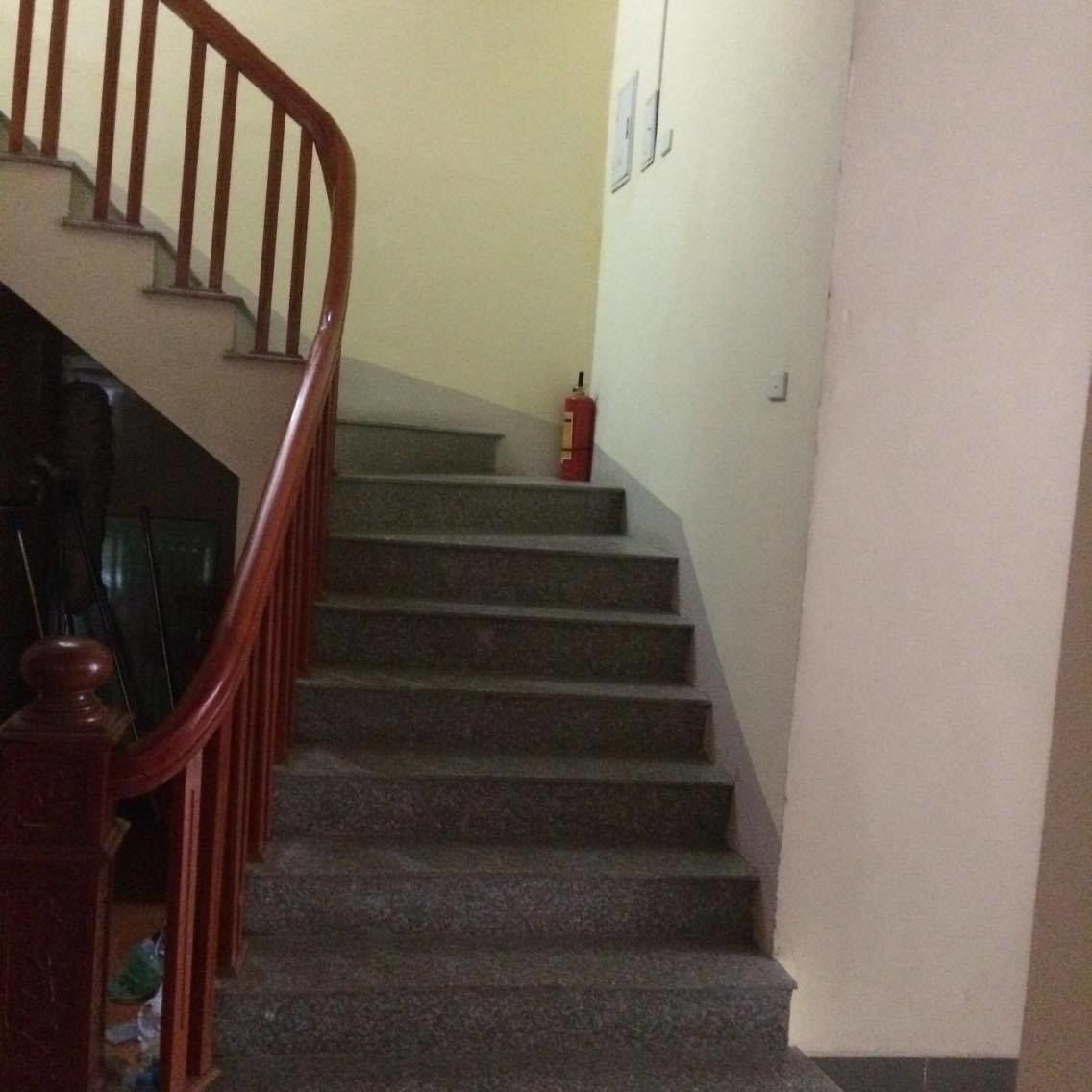 A staircase with wooden handrails and a fire extinguisher on the landing.