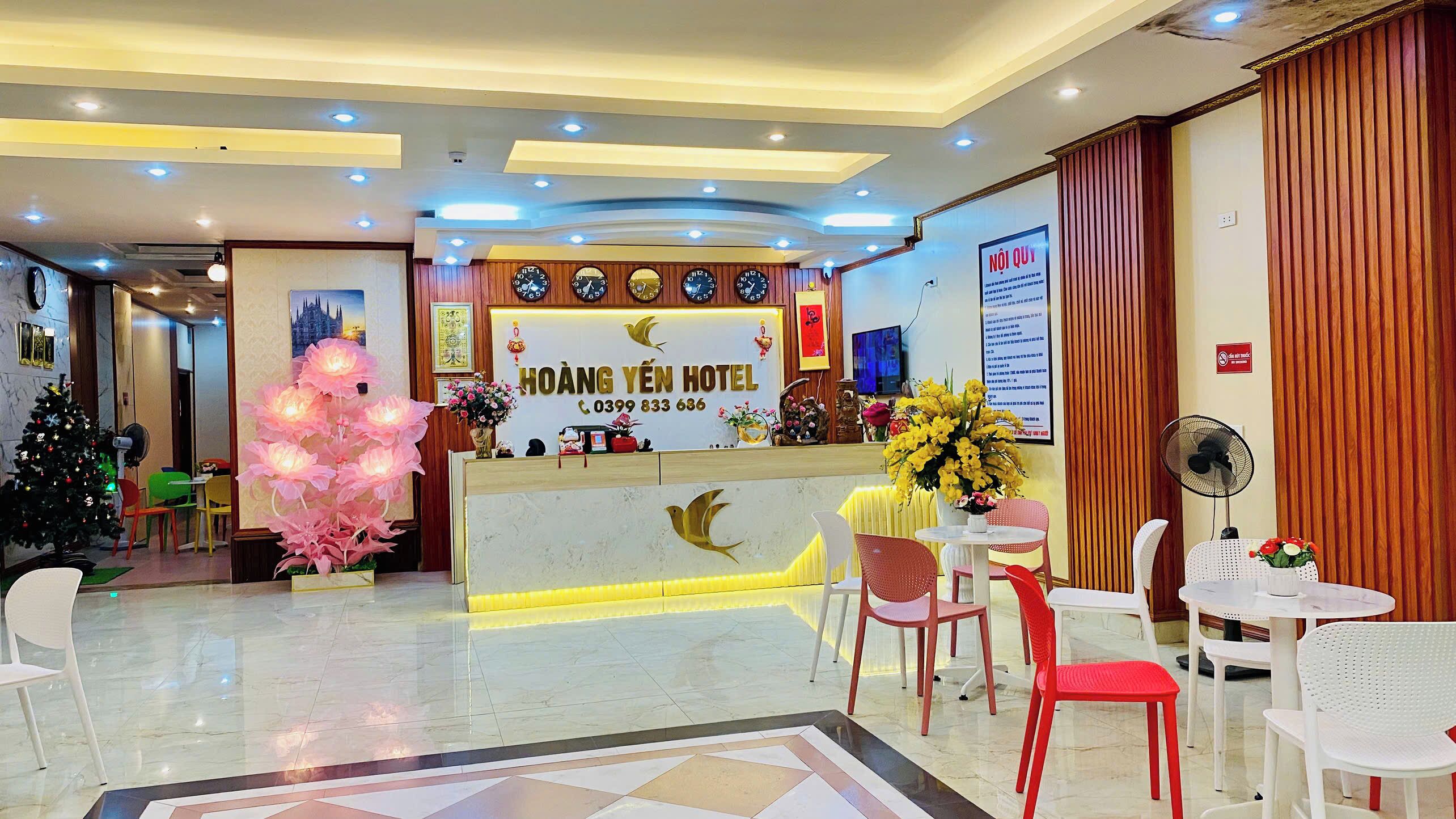 A hotel reception area with a reception desk, chairs, a Christmas tree, and a wall clock.