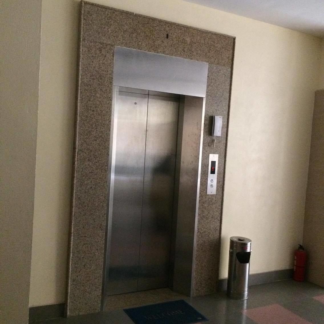 Un ascensor con detalles metálicos, un panel de control y un extintor cerca.