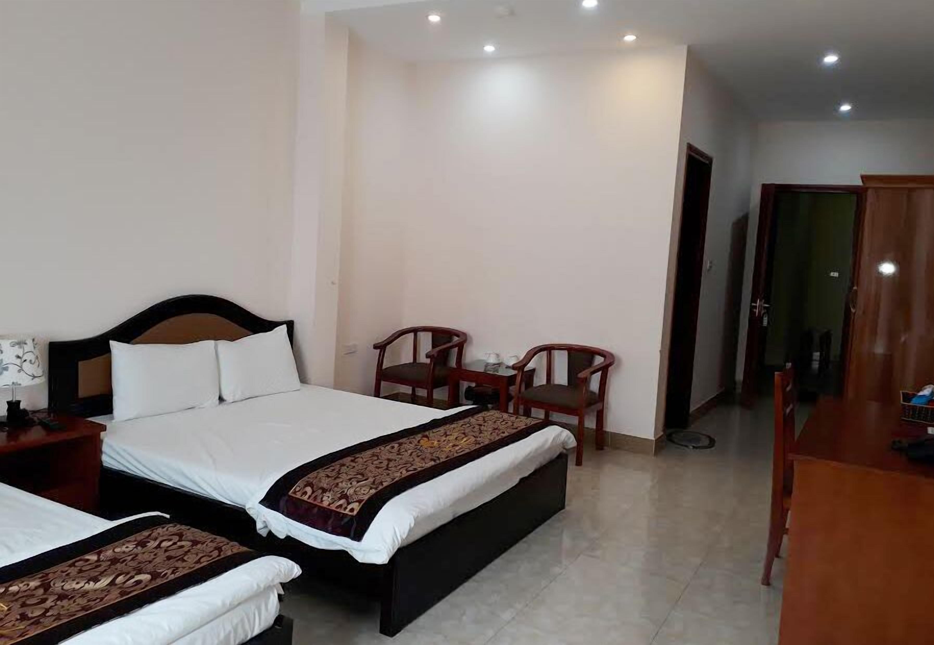 Una habitación de hotel con una cama grande, dos mesitas de noche, un escritorio y dos sillas.
