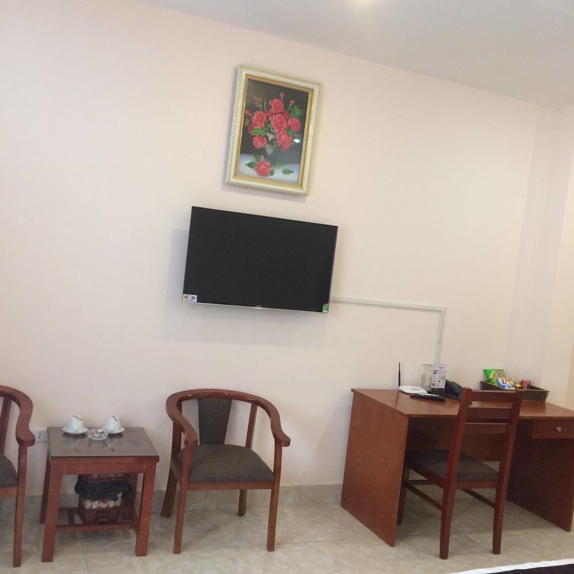 Une pièce avec un téléviseur fixé au mur, un bureau avec une chaise et deux chaises supplémentaires.