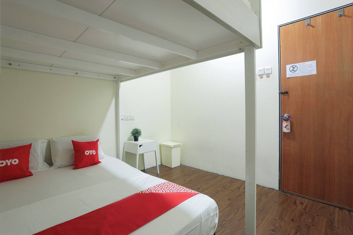A hotel room with a bed, a desk, a small table, and a door.