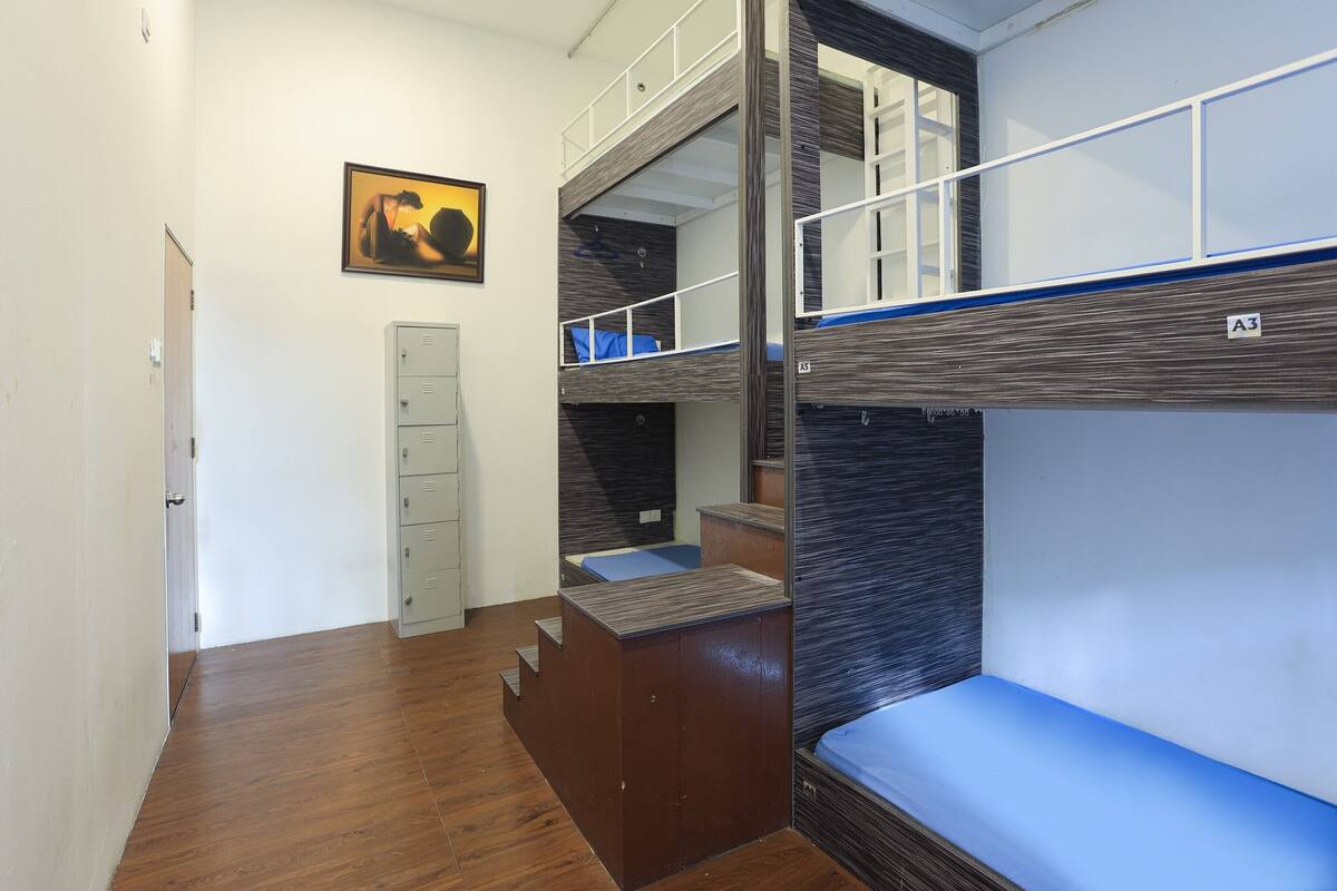 A bunk bed room with a wooden floor, a desk, and a cabinet.