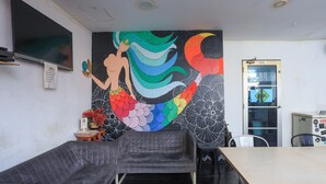 Une pièce comprenant un canapé, une table et une fresque murale représentant une sirène.