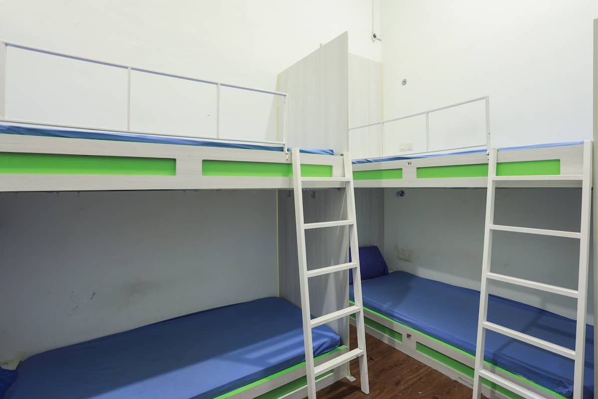A room with bunk beds, each with a ladder and a blue mattress.