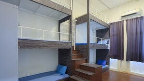 Une chambre avec un lit superposé, un escalier en bois et une fenêtre avec des rideaux.