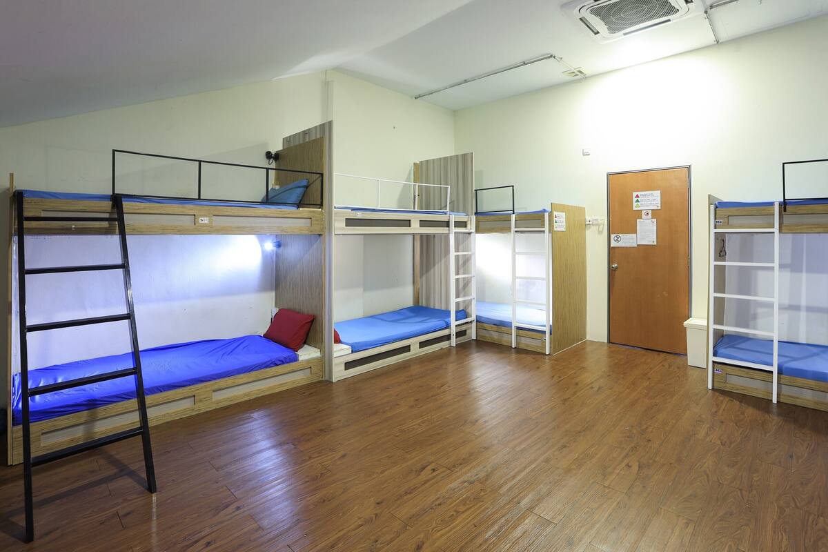 A dormitory room with bunk beds, a ladder, and a door with a notice.