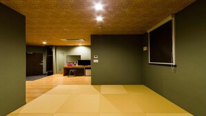 Een kamer met een houten plafond, een bureau met een computer, een stoel en een groot raam.