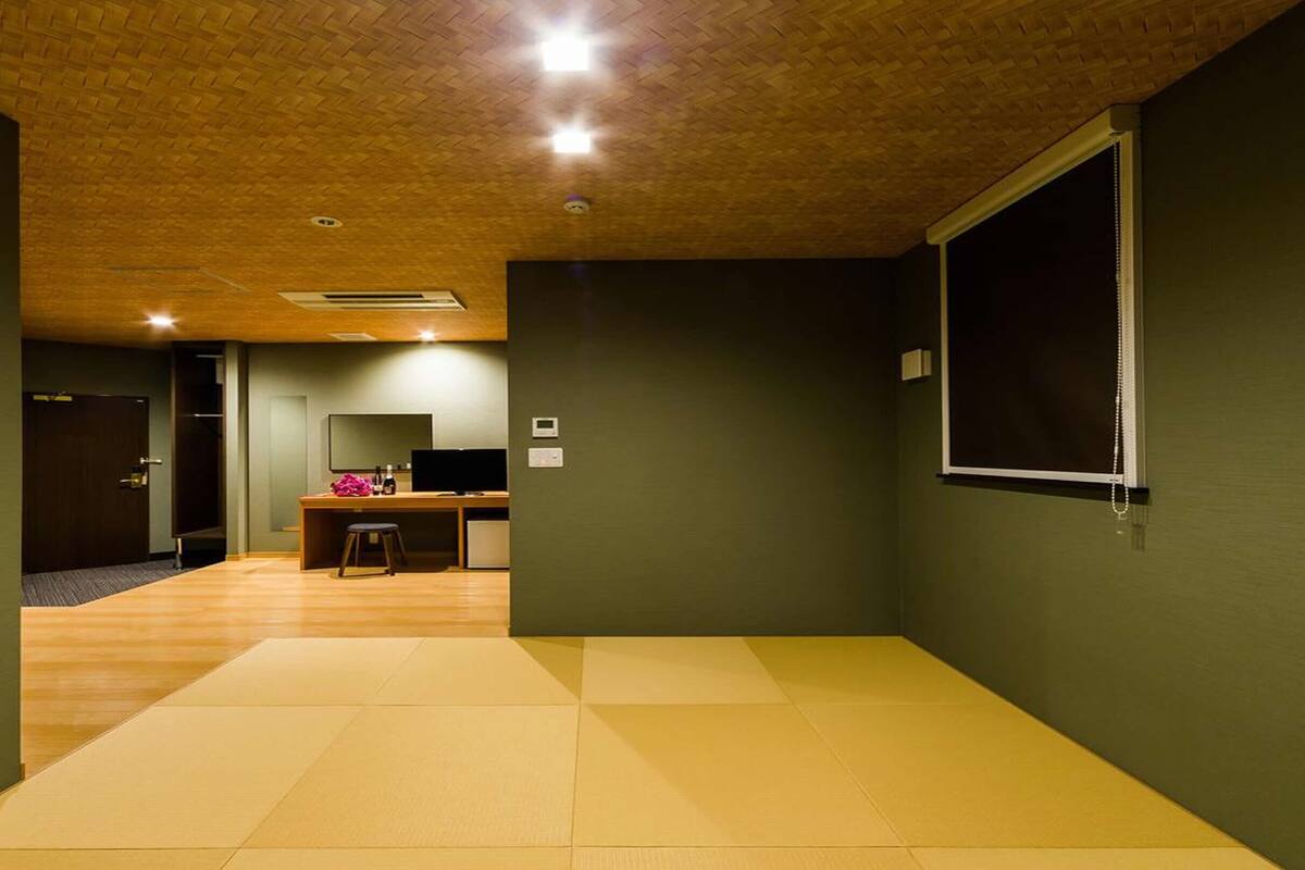 Una habitación con techo de madera, un escritorio con computadora, una silla y un ventanal grande.