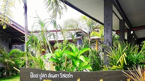 Placa do Popular Lanta Resort cercado por plantas tropicais.