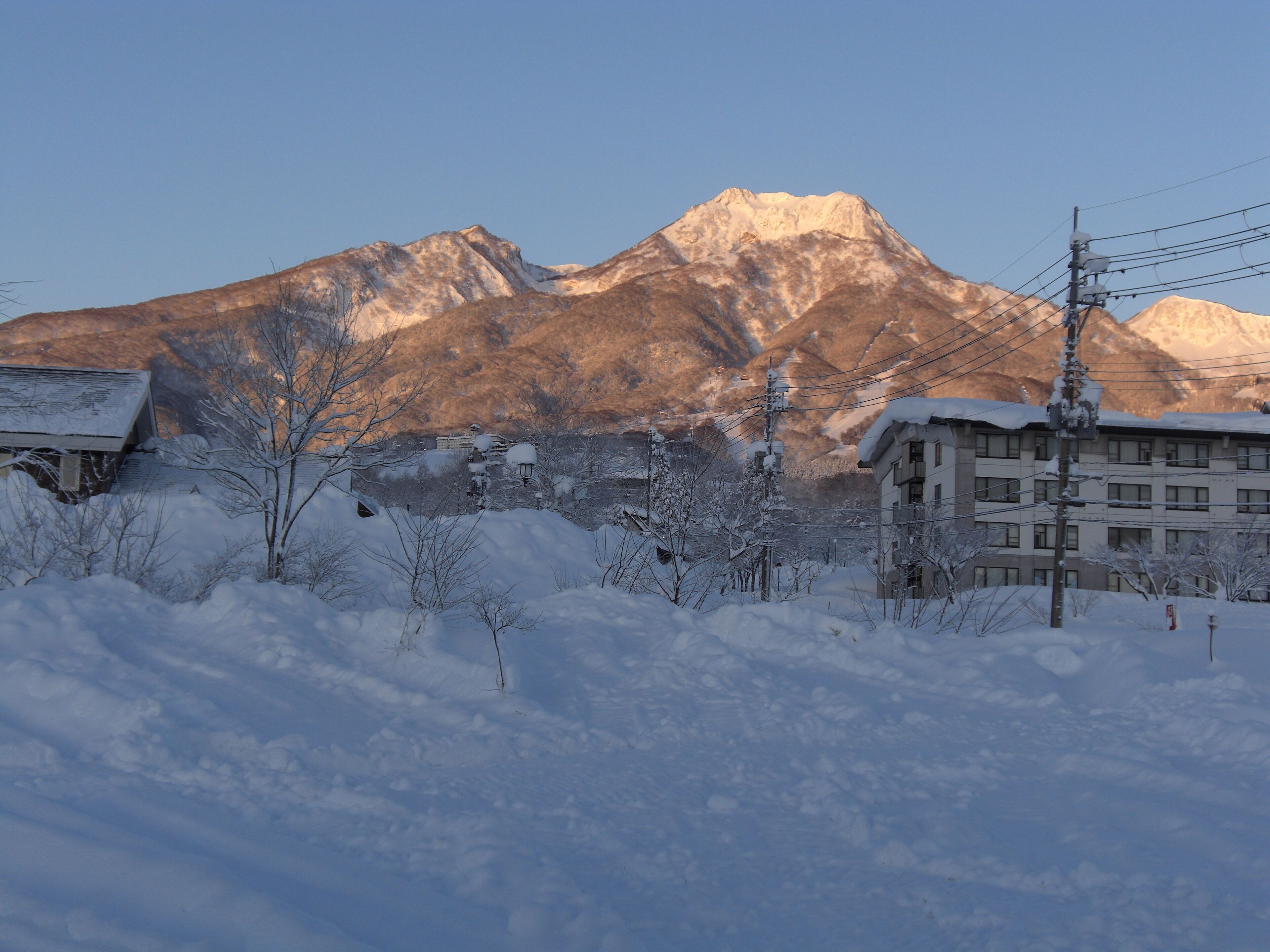 Un monte cubierto de nieve con un edificio en primer plano.