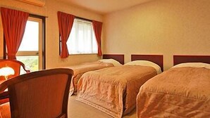 Een hotelkamer met twee eenpersoonsbedden, een bureau met stoel, en een raam met gordijnen.