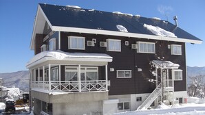 Een meerhoog gebouw met een balkon, een trap en een met sneeuw bedekt dak.