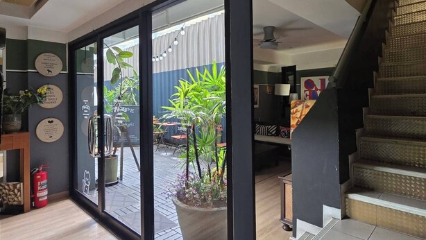 A modern interior with a glass door leading to a balcony with potted plants. - Somewhere to Escape - Hometel (Bangkok)