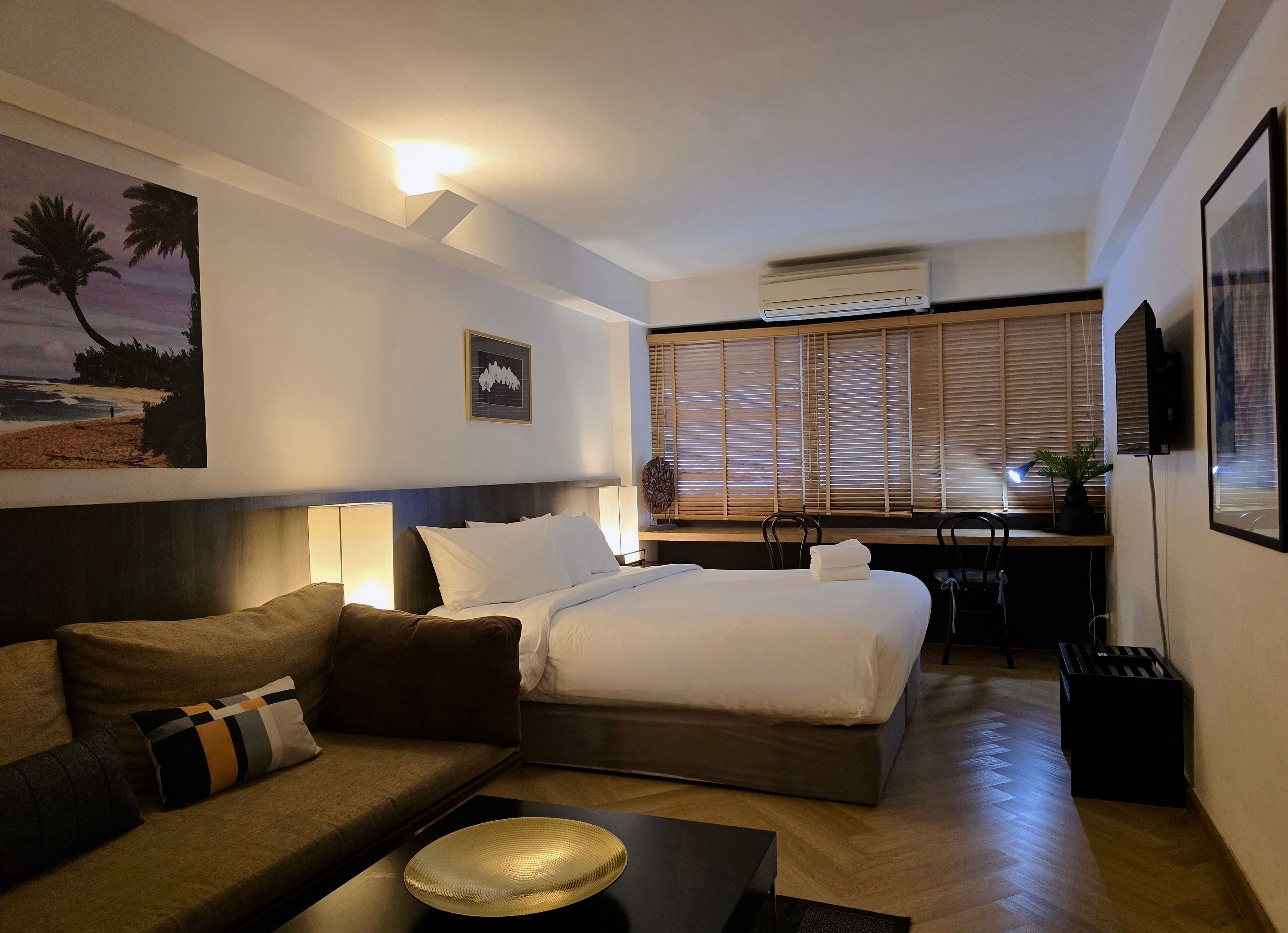 A hotel room with a bed, a sofa, a desk, and a television.