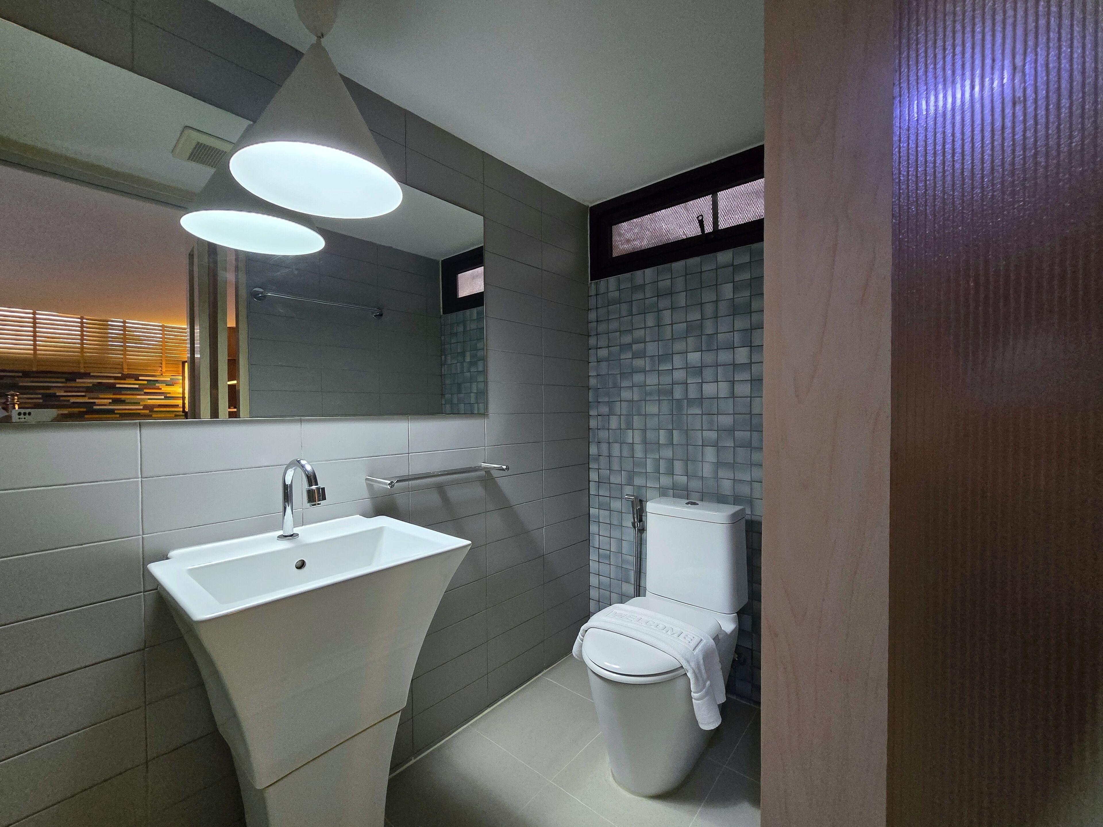 A modern bathroom with a white sink, a toilet, and a mirror.