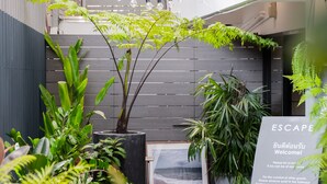 A modern outdoor area with various plants, a framed picture, and a sign indicating a no-smoking policy. - Somewhere to Escape - Hometel (Bangkok)