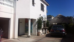 A white building with a garage, a mural, and a parked car. - Upper Room Guest House (Francistown)