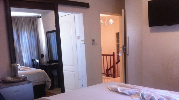 A hotel room with two beds, a desk with a telephone, and a mirror. - Upper Room Guest House (Francistown)