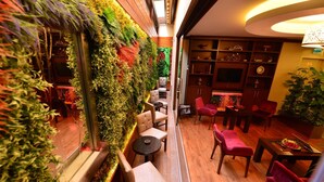 A cozy indoor seating area with a vertical garden wall, wooden flooring, and a variety of seating options including chairs and tables. - Golden Siyav Hotel (Istanbul)