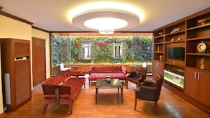 A modern living room with a red sofa set, a coffee table, and a television on a wooden cabinet. - Golden Siyav Hotel (Istanbul)
