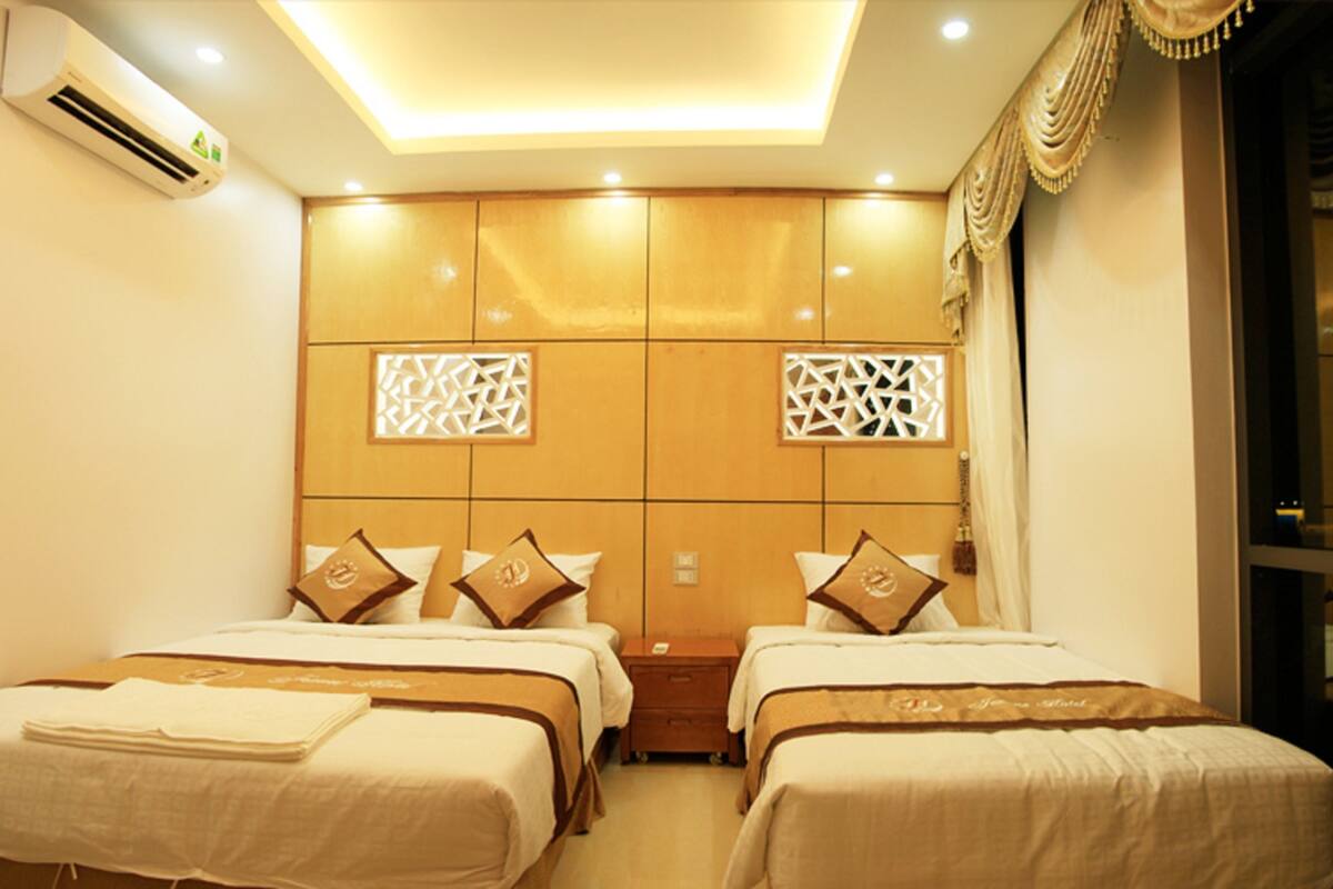 A hotel room with two beds, a large wardrobe, and a ceiling light fixture.