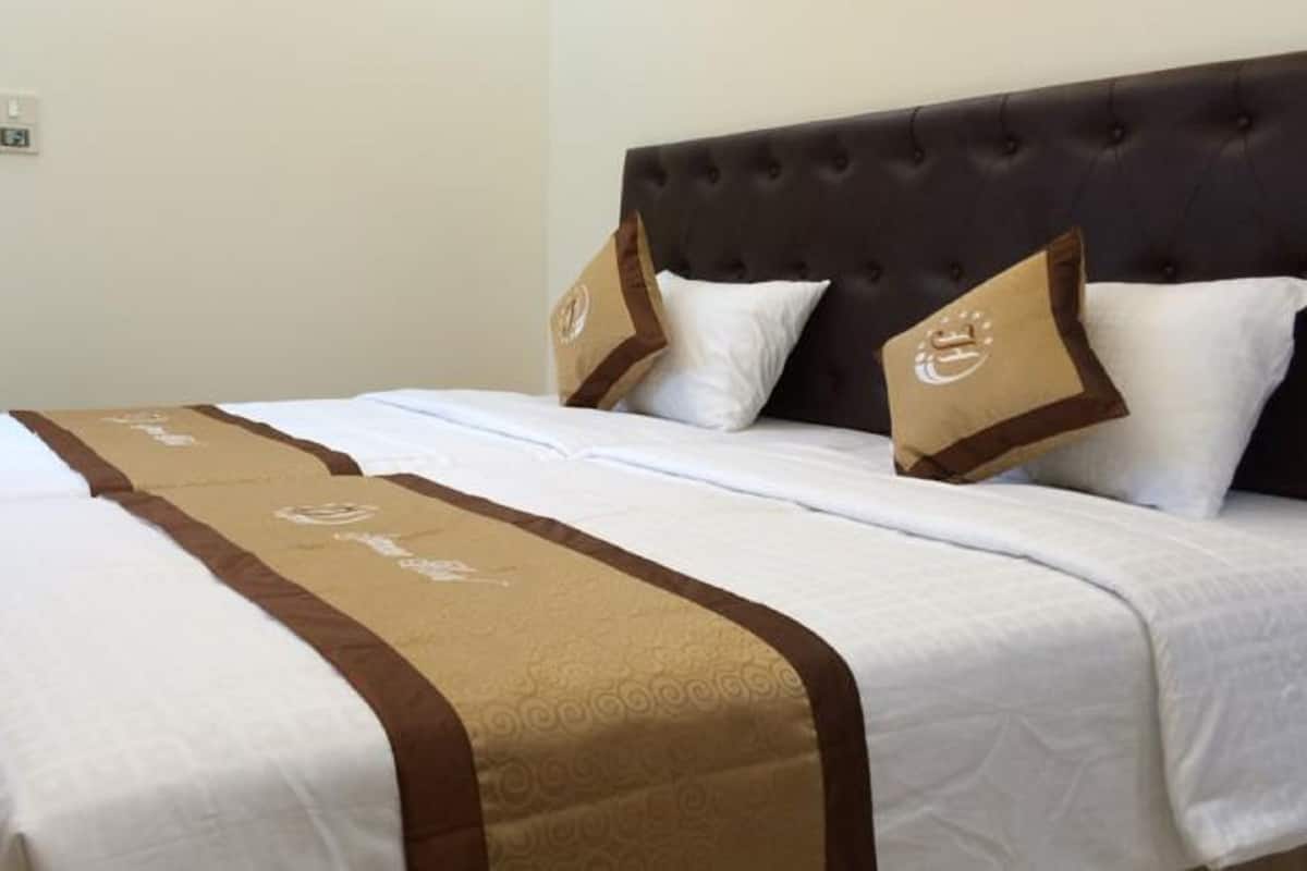A double bed with a brown headboard and white bedding.