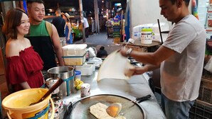 A street food vendor preparing food on a portable stove. - Sathorn Terrace Apartment (Bangkok)