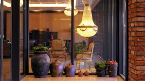 A modern interior with a large chandelier, a grand piano, and a seating area with a large chair and a sofa. - Odri Inn Jeju (Jeju City)