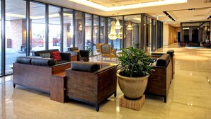 A spacious lobby with modern furniture, large windows, and a large potted plant. - Odri Inn Jeju (Jeju City)