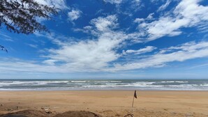 Une plage avec un drapeau signalant la limite de la zone balnéaire, une plage de sable et des vagues.