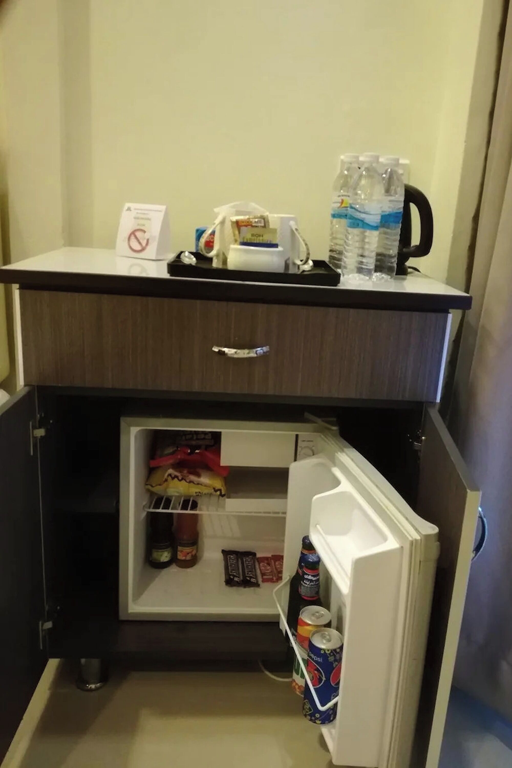 A compact minibar with a refrigerator, a coffee maker, and bottled water.