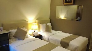 A hotel room with two beds, a nightstand, a lamp, a dresser, and a mirror on the wall.