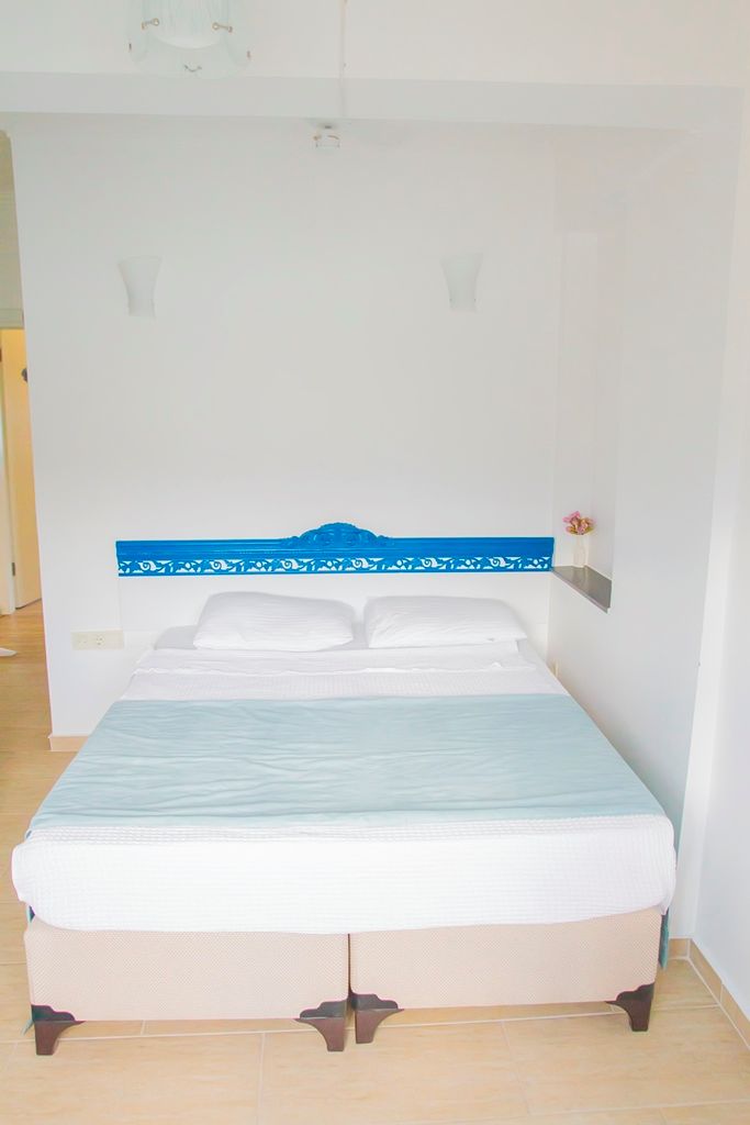 A single bed with a blue headboard, white bedding, and a light blue mattress cover.