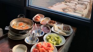 A table with various dishes and a view of the sea through a window. - Uzum Iskelesi Butik Otel (Karaburun)