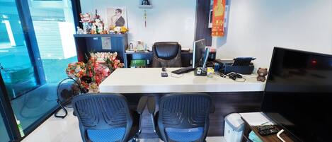 An office with two chairs, a desk, a computer, and a TV.