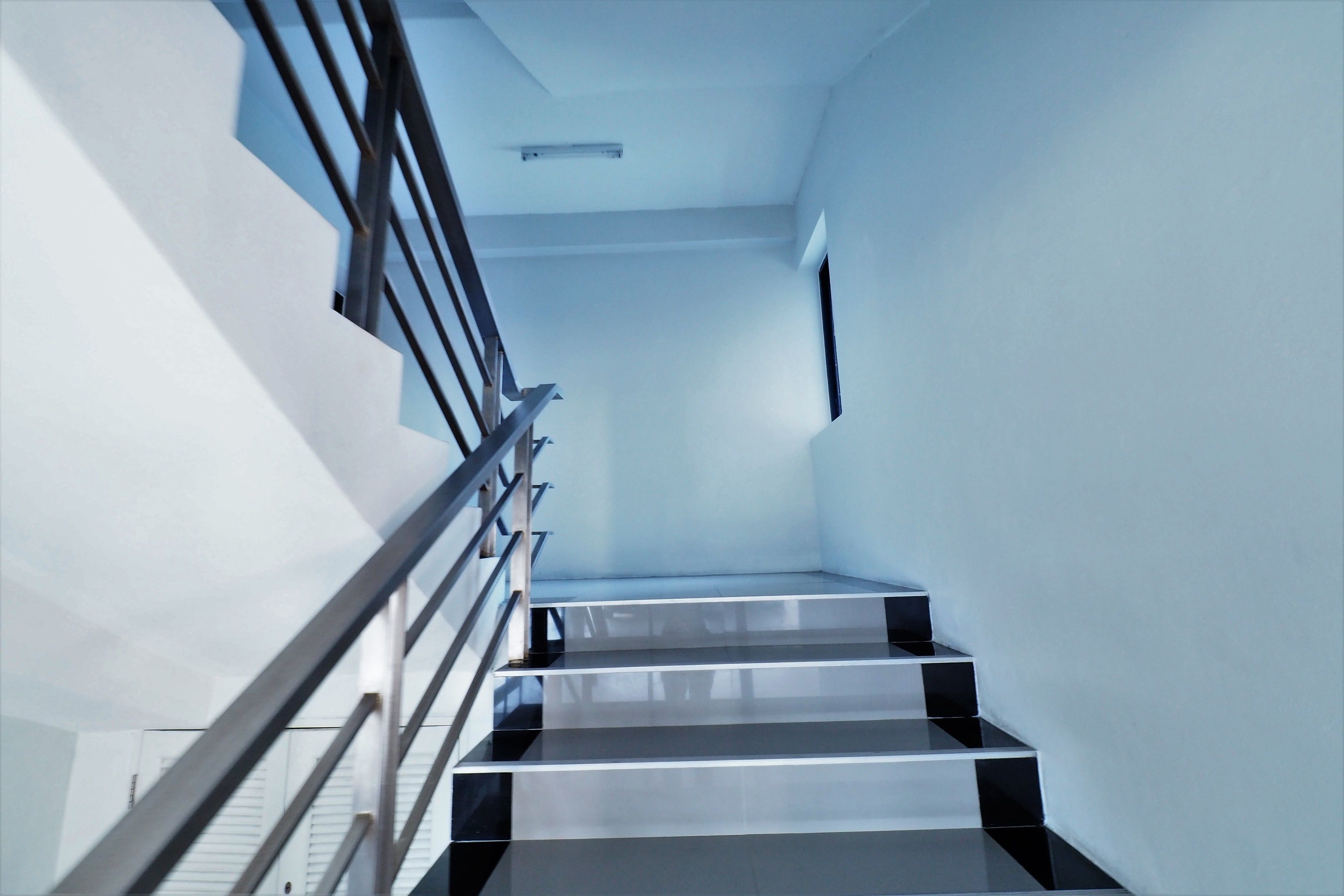 Una escalera moderna con barandas metálicas y un tramo recto que lleva a una plataforma.
