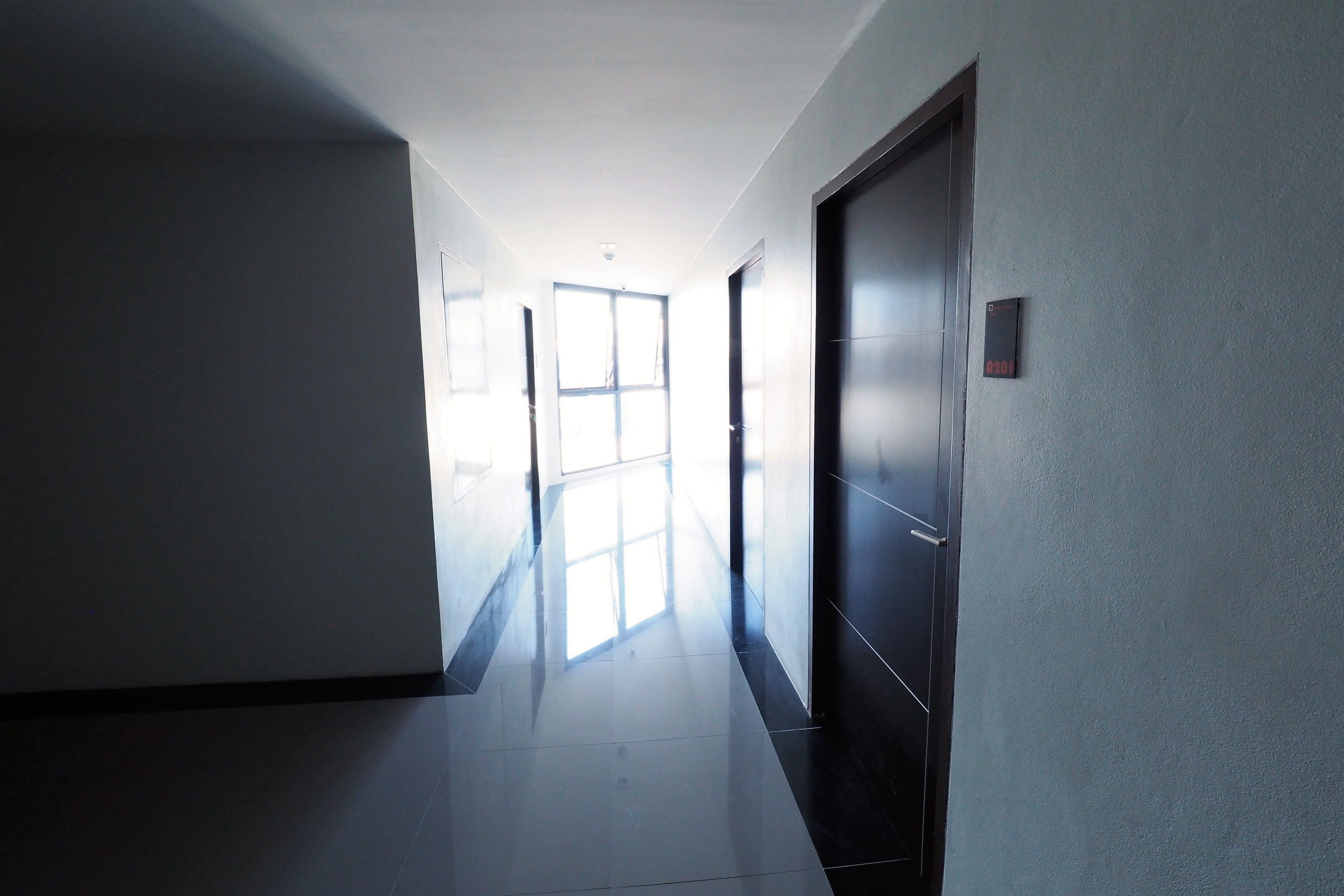 A hallway with a door on the right, a window at the end, and a light source from the window.