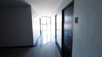 A hallway with a door on the right, a window at the end, and a light source from the window.