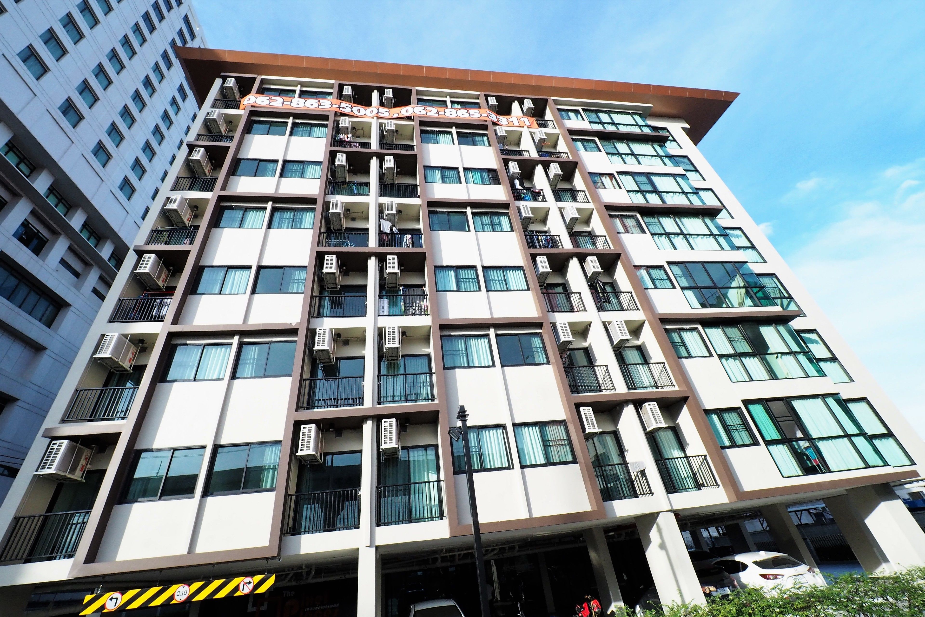 Un immeuble à plusieurs étages doté de balcons, de climatiseurs et surplombant un ciel dégagé.