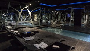 A modern indoor pool area with lounge chairs and a unique ceiling structure. - A Point Arezzo Park Hotel (Arezzo)