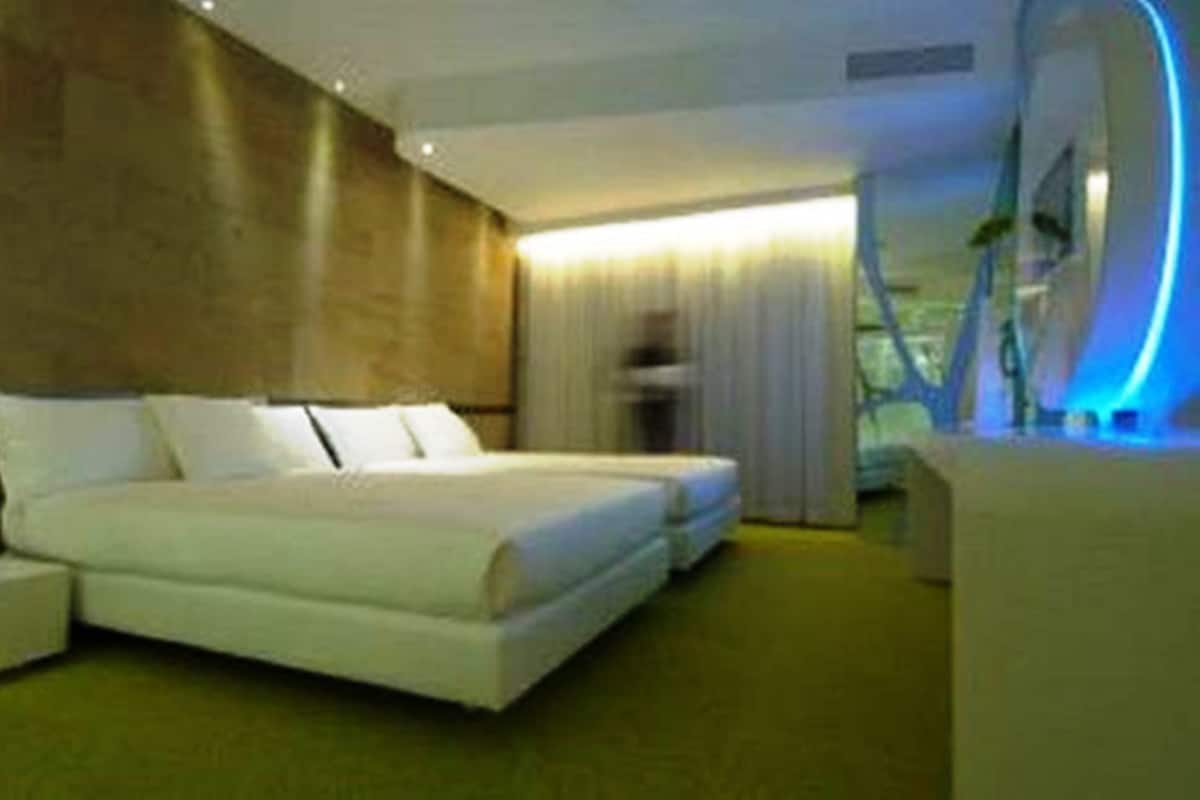 Une chambre d’hôtel moderne avec un grand lit, un petit coin salon et une vue sur l’extérieur.