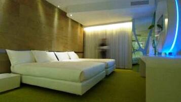 Une chambre d’hôtel moderne avec un grand lit, un petit coin salon et une vue sur l’extérieur.