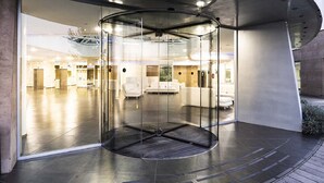 A modern lobby with a glass revolving door, a seating area with white sofas, and a spacious interior. - A Point Arezzo Park Hotel (Arezzo)