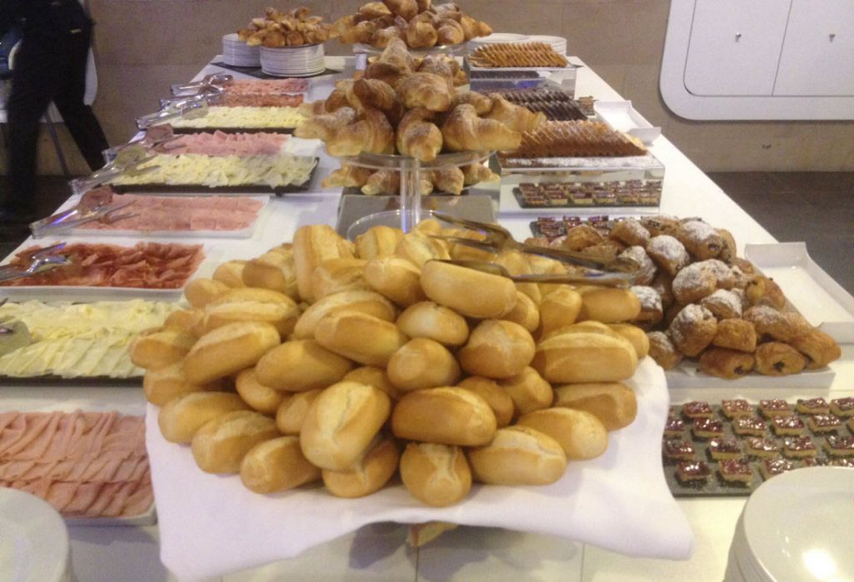 A buffet table with various food items including pastries, sandwiches, and desserts.