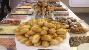 A buffet table with various food items including pastries, sandwiches, and desserts.