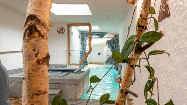 Un espace bien-être comprenant un bain à remous, des marches en pierre et une vue sur une formation rocheuse naturelle.