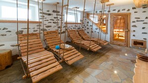 Une salle équipée de fauteuils de massage en bois, avec un sol et un mur en pierre.